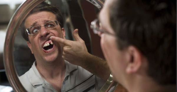Man kijkt in de spiegel en ziet dat een van zijn tanden in uitgevallen